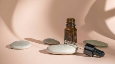 A medicine bottle with a pipette and stones on a beige background. The concept of treatment and body care using natural remedies.