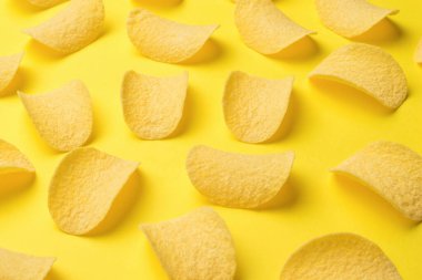 Scattered potato chips on a bright yellow background. A popular potato dish.