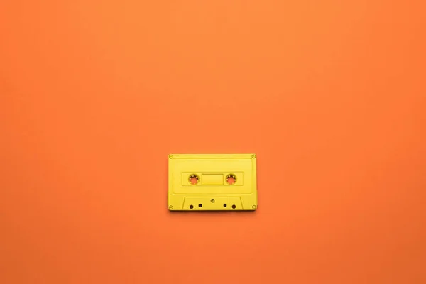 橙色背景上带有磁带的亮黄色盒带 听音乐用的老式复古设备 平躺在床上 — 图库照片