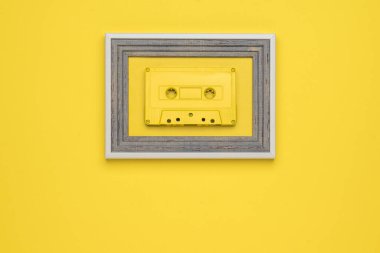 Sarı arka planda çerçeveli sarı bir kaset. Müzik dinlemek için modaya uygun retro ekipmanlar. Düz yatıyordu.