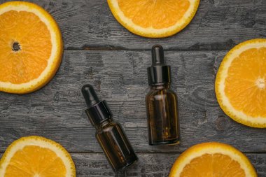 Two bottles of perfume water and pieces of orange on a wooden background. Natural cosmetics and medicinal products.