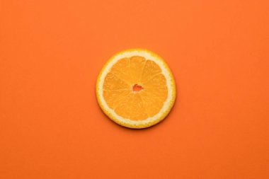 A piece of fresh orange on an orange background. A popular tropical fruit. Flat lay.