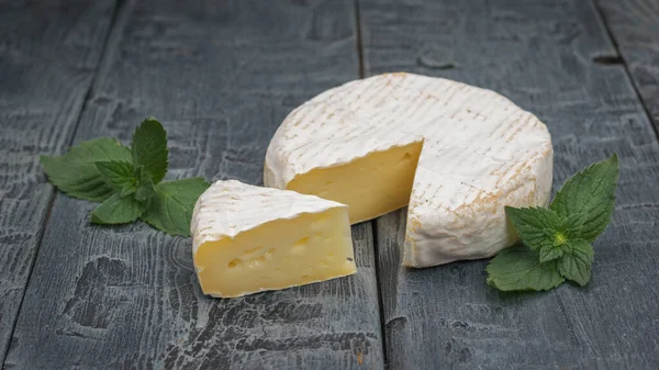 Camembert Cheese Cut Piece Mint Leaves Black Wooden Table Product — Zdjęcie stockowe