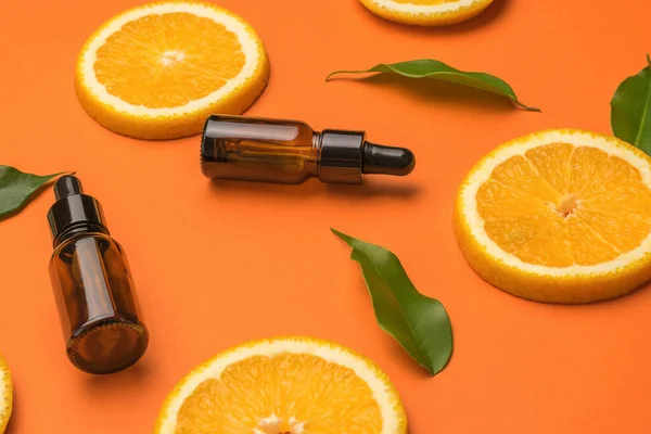 Orange slices, leaves and medical bottles on an orange background. The concept of therapy with natural remedies.