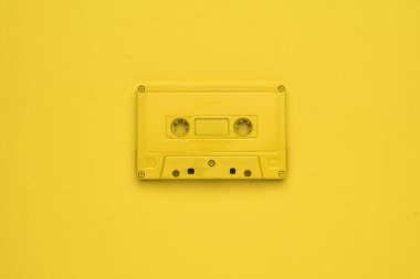 Sarı arka planda tek renkli sarı bir teyp görüntüsü. Müzik dinlemek için modaya uygun retro ekipmanlar. Düz yatıyordu.