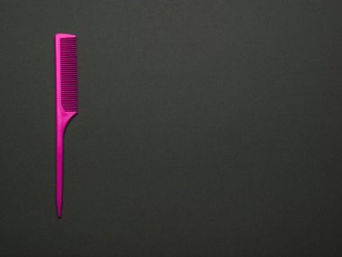 Siyah arka planda parlak kırmızı bir tarak. Saç bakımı için bir alet. Düz yatıyordu.