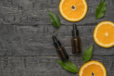 Portakal dilimleri ve ahşap zemin üzerinde pipetleri olan iki şişe. Doğal kozmetik ürünleri ve tıbbi ürünler. Metin için yer.