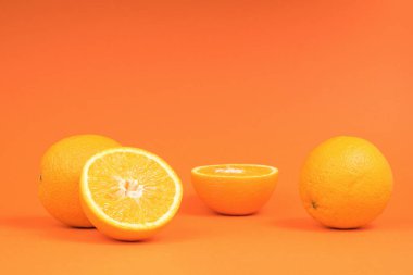 Turuncu arka planda tam ve dilimlenmiş portakallar. Popüler bir tropikal meyve.