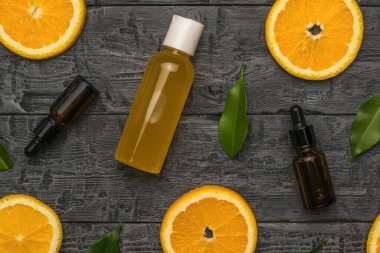 Portakallar, yapraklar, göz damlası olan şişeler ve ahşap arka planda bir şişe meyve suyu. Doğal ilaçlarla terapi kavramı..