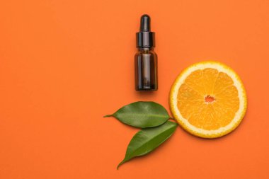 Göz damlası olan bir şişe, turuncu arka planda bir parça turuncu ve yeşil yaprak. Doğal ilaçlarla terapi kavramı..