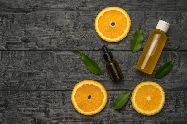 Üç parça portakal, bir şişe göz damlası ve ahşap bir masada bir şişe meyve suyu. Doğal ilaçlarla terapi kavramı..