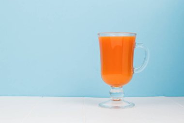 Mavi arka planda beyaz bir masada bir bardak meyve püresi. Sağlıklı beslenme kavramı.