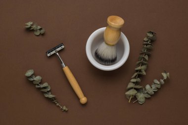 Okaliptüs tozu, ahşap bir jilet ve kahverengi arka planda kasesi olan bir fırça. Bakım için erkek aksesuarları. Düz yatıyordu.