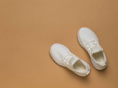 Kahverengi arka planda bağcıkları olan şık beyaz ayakkabılar. Spor tarzı. Düz yatıyordu. Yukarıdan görünüşü.