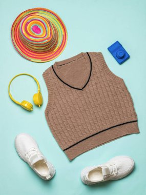 Mavi arka planda spor ayakkabılar, yelek, şapka, kamera ve kulaklık. Modaya uygun klasik örgü kıyafetler..