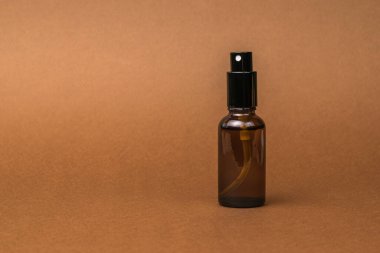 Kahverengi arka planda cam sprey şişesi. Doğal tedavi ve vücut bakımı kavramı.