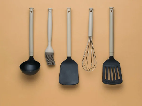 茶色の背景に黒とベージュのキッチンアクセサリー プラスチックキッチンツール — ストック写真