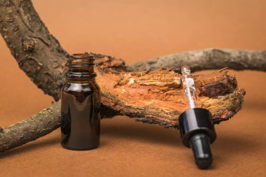 Açık bir şişe ve kahverengi arka planda eski bir ağaç. Doğal minerallere dayalı kozmetik ve tıbbi ürünler. Doğal ilaçlar kullanan tedavi ve vücut bakımı kavramı..