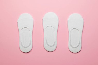 Pembe arka planda üç çift beyaz kadın kısa çorabı. Şık bir spor aksesuarı..