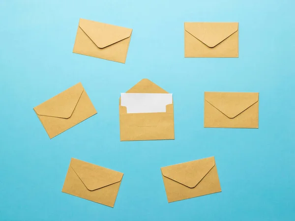 An open postal envelope with a white sheet on a background of closed envelopes on a blue background. The concept of mail correspondence. Flat lay.