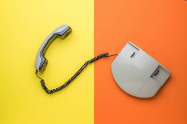 Sarı ve turuncu arka planı olan eski bir telefonun üst görüntüsü. Retro iletişim araçları. Düz yatıyordu.