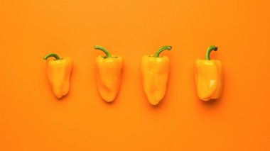 Turuncu arka planda dört olgun portakal biberi. Vejetaryen yemeği. Taze sebze mahsulü..