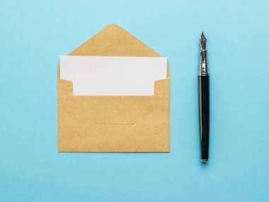 Bir dolmakalem ve açık bir posta zarfı. Mavi arka planda beyaz bir çarşaf. Posta yazışmaları kavramı. Düz yatıyordu.
