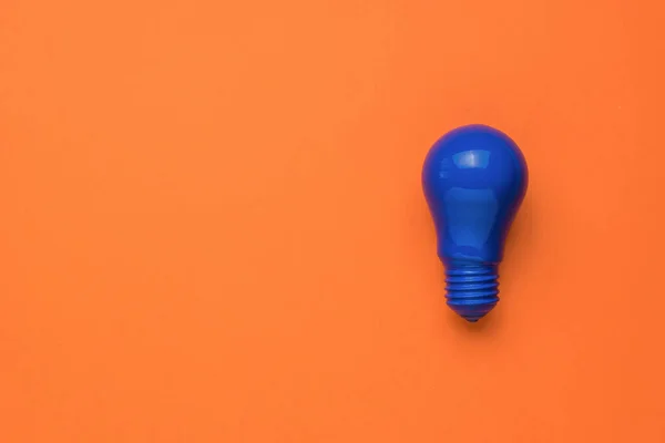 Eine Leuchtend Blaue Glühbirne Auf Orangefarbenem Hintergrund Minimalismus Das Konzept — Stockfoto