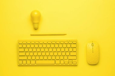 Sarı arka planda fareli sarı bir klavye, bir kalem ve bir ampul. İş ve minimalizm kavramı. Tek Renkli.