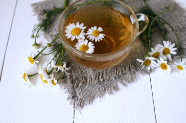 Cup of camomile tea with camomile flowers clipart