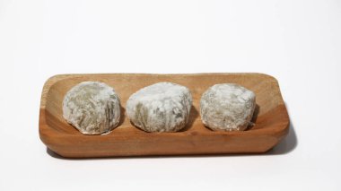 Mochi, a sweet dessert or rice cake filled with chocolate or mung beans, and coated with sesame seeds Mochi cake on a plate with a white background.