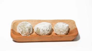 Mochi, a sweet dessert or rice cake filled with chocolate or mung beans, and coated with sesame seeds Mochi cake on a plate with a white background.