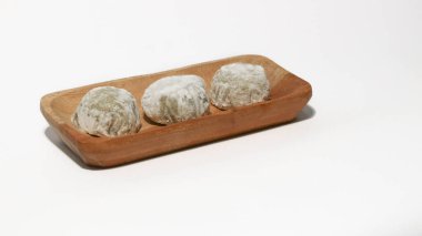 Mochi, a sweet dessert or rice cake filled with chocolate or mung beans, and coated with sesame seeds Mochi cake on a plate with a white background.