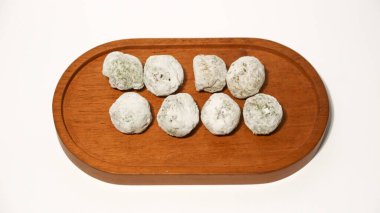 Mochi, a sweet dessert or rice cake filled with chocolate or mung beans, and coated with sesame seeds Mochi cake on a plate with a white background.
