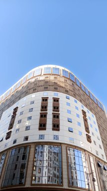 Yukarı bakan modern bir cam ve beton binanın soyut bir görüntüsü. Bir ofis binasının mimari dış görünüşü. Gökyüzüne karşı yükselen yüksek binaları olan bir şehir manzarası.