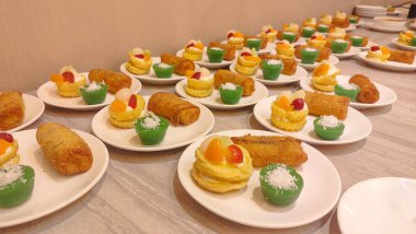 Beyaz tabaklarda servis edilen çeşitli geleneksel Endonezya kekleri ve atıştırmalıkları, çekici renkler ve çeşitli dokular sergiliyor..