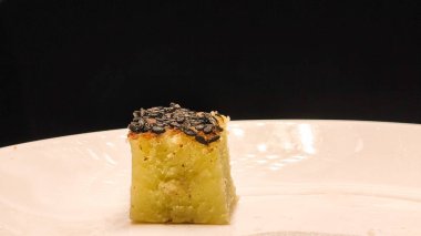 Bika Ambon, beyaz tabakta kare dilimlenmiş Endonezya bal peteği keki. Un, tapyoka, hindistan cevizi kreması, limon yaprağı ve şekerden yapılır.. 