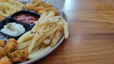 Mix Platter, paket servis yemekleri: mozzarella çubukları, soğan halkaları, patates kızartması, tavuk nugget ve ahşap bir tahtanın üzerindeki sos. afiş, menü, metin için tarif sahibi.