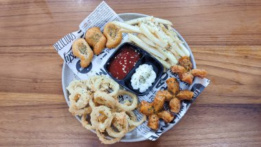 Mix Platter, paket servis yemekleri: mozzarella çubukları, soğan halkaları, patates kızartması, tavuk nugget ve ahşap bir tahtanın üzerindeki sos. afiş, menü, metin için tarif sahibi.