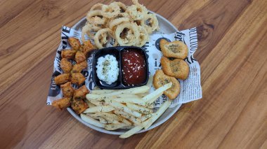 Mix Platter, paket servis yemekleri: mozzarella çubukları, soğan halkaları, patates kızartması, tavuk nugget ve ahşap bir tahtanın üzerindeki sos. afiş, menü, metin için tarif sahibi.