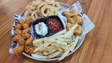 Mix Platter, paket servis yemekleri: mozzarella çubukları, soğan halkaları, patates kızartması, tavuk nugget ve ahşap bir tahtanın üzerindeki sos. afiş, menü, metin için tarif sahibi.