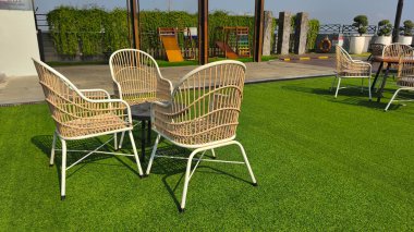 İçinde kavisli gri bir kanepe, kestane rengi bir aksanlı sandalye ve eşsiz geometrik sehpaların etrafına dizilmiş bej bir koltuk olan modern bir oturma odası..