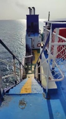 Güvertede halatları olan büyük bir feribot, küçük Obak 'ı yakından görüyor.