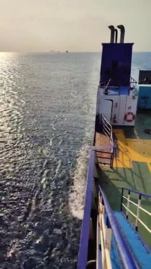 Güvertede halatları olan büyük bir feribot, küçük Obak 'ı yakından görüyor.