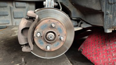 Görünür pas, otomotiv tamiri ve bakım konsepti olan bir araba fren diski ve tekerlek merkezinin yakın çekimi. Tamir sırasında araç fren sistemi açığa çıktı, atölyede eskimiş fren pervanesi ve süspansiyon parçaları.