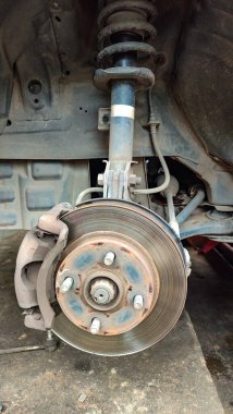 Görünür pas, otomotiv tamiri ve bakım konsepti olan bir araba fren diski ve tekerlek merkezinin yakın çekimi. Tamir sırasında araç fren sistemi açığa çıktı, atölyede eskimiş fren pervanesi ve süspansiyon parçaları.