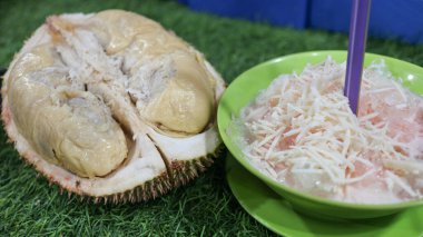 Çimenli arka planda yeşil bir kasede rendelenmiş peynirli taze Durian dondurması. Güneydoğu Asya 'da popüler bir sokak yemeği olan rendelenmiş peynirli geleneksel Durian tatlısı..