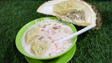 Çimenli arka planda yeşil bir kasede rendelenmiş peynirli taze Durian dondurması. Güneydoğu Asya 'da popüler bir sokak yemeği olan rendelenmiş peynirli geleneksel Durian tatlısı..
