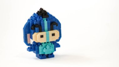 Plastik tuğlalardan yapılmış, beyaz arka planda minimalist tarzda izole edilmiş şirin mavi blok oyuncağı karakteri. Birbirine kenetlenmiş bloklardan inşa edilmiş küçük mavi pikselli biblo, temiz beyaz arka planda yaratıcı oyuncak tasarımı.