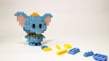 Beyaz arka planda plastik yapı taşlarından yapılmış şirin mavi bir fil figürü. Renkli yapı taşlarıyla yapılmış oyuncak bir fil. Minimalist bir stüdyo resmi..